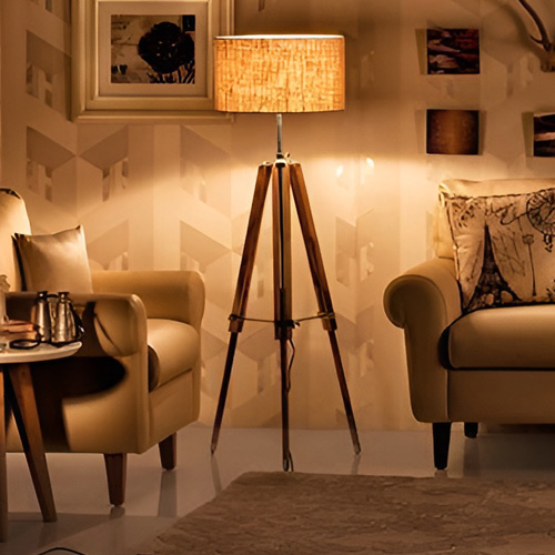 A tripod conical shade lamp sitting in a living room, next to a couch.